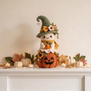 May include: A crocheted ghost figure wearing a sage green pointed hat with a small star charm, a yellow scarf, and holding a small orange pumpkin. The ghost sits atop a large, round, orange crocheted pumpkin with a black stitched jack-o'-lantern face.