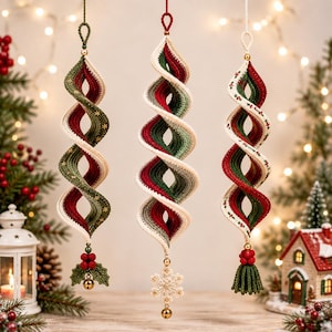 May include: Three hanging spiral ornaments crafted from crocheted yarn in red, green, and cream. Each ornament features a unique bottom accent: one with holly leaves and berries, one with a snowflake, and one with a green tassel and red berries.
