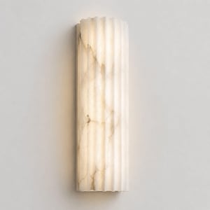 May include: A vertical wall sconce featuring a semi-cylindrical shape with a fluted, ribbed surface. The fixture is crafted from a translucent, off-white stone material with natural grey veining, emitting a soft, warm glow from within.