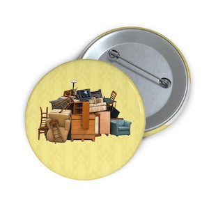 May include: A round pin-back button featuring a yellow background with a repeating chevron pattern. The center displays a chaotic pile of various household furniture items, including wooden chairs, a television, a cabinet, and upholstered armchairs.