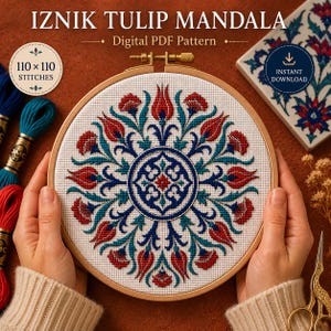 Op de afbeelding: Een ronde houten borduurring met een kruissteekproject genaamd Iznik Tulip Mandala. Het ontwerp toont een symmetrisch patroon van rode tulpen en blauwe bloemmotieven op witte stof. De tekst bevat de vermelding 110 x 110 stitches.