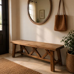 May include: A rectangular wooden bench featuring a natural brown finish and a sturdy base with an X-shaped support structure. The bench has a smooth, flat top surface and four thick, straight legs, providing a stable seating option for an entryway.