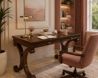 May include: A dark wood desk with curved legs and two drawers featuring silver knobs. On the desk sits a gold lamp, a stack of books, a small bowl, a candle, and a mug. A pink upholstered office chair with a dark wood base and wheels is positioned.