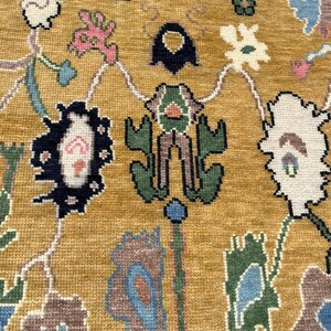 May include: A mustard yellow area rug featuring a woven pattern of stylized floral and botanical motifs in shades of dark blue, forest green, light blue, white, and soft pink. The design consists of interconnected organic shapes and vines.