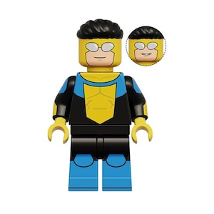 Könnte beinhalten: Eine Kunststoff-Spielfigur mit gelbem Kopf, schwarzem Haar und weißer Brille, bekleidet mit einem blau-schwarzen Anzug mit gelbem Brustemblem. Ein zusätzlicher austauschbarer gelber Kopf mit anderem Gesichtsausdruck liegt bei.