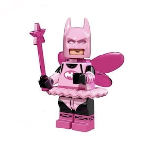 May include: A pink Batman minifigure wearing a tutu and fairy wings. The figure has a bat-eared cowl, a chest emblem, and black arm and leg details. It holds a translucent pink star-tipped wand in one hand. The design features a mix of light and dark pink tones with black accents on the arms, legs, and waist area.
