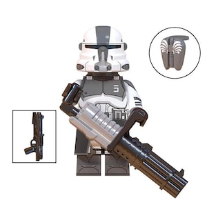 Puede incluir: Una minifigura de soldado de juguete con casco y armadura blancos y grises con una placa pectoral negra. La figura sostiene un gran cañón bláster giratorio negro y plateado. Se incluyen un bláster negro separado y un accesorio de mochila gris.