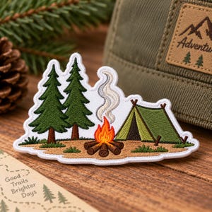 May include: An embroidered patch featuring a camping scene with two dark green pine trees, a bright orange and yellow campfire with gray smoke rising, and a green A-frame tent on a tan ground, all outlined with a white border.
