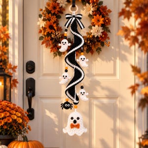 May include: A crochet wall hanging featuring a black and white spiral ribbon topped with a striped bow. Five small white ghosts and one black spider are attached to the spiral with wooden beads. A larger white ghost with an orange bow hangs below.