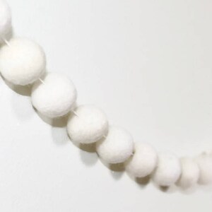 May include: A white felt ball garland with a string of white felt balls strung together.