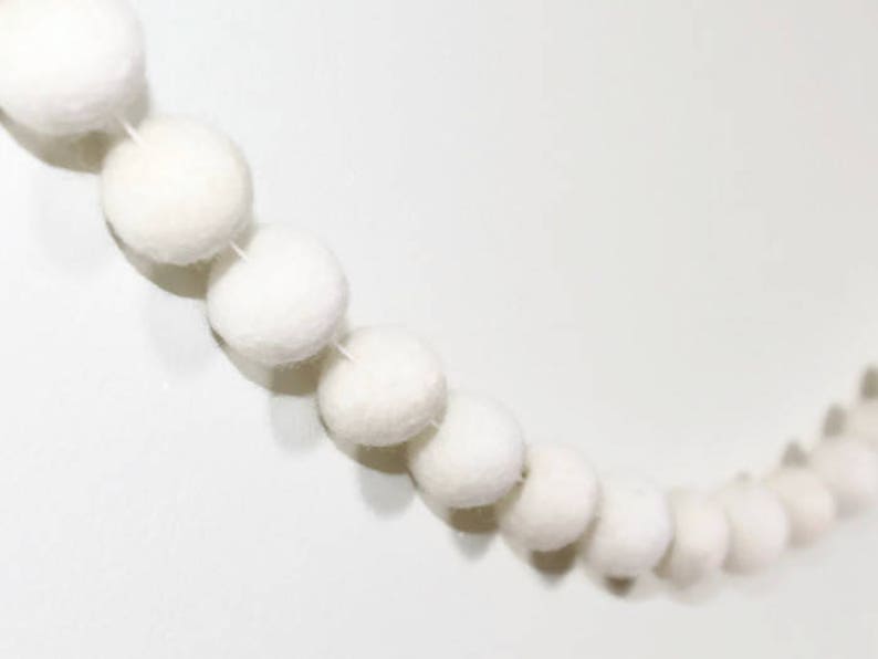 May include: A white felt ball garland with a string of white felt balls strung together.