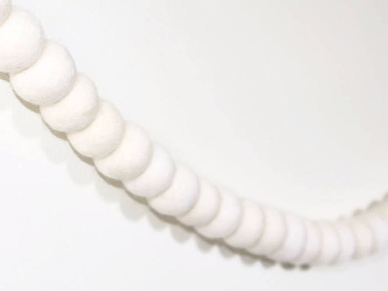 May include: A white felt ball garland, a string of white pom poms connected together, perfect for adding a touch of whimsy to any space.