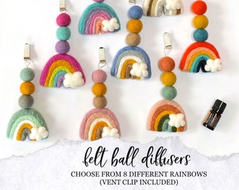 May include: Eight felt rainbow diffusers with a white cloud and a felt ball chain. Each diffuser has a metal clip for attaching to a vent. The text "felt ball diffusers" and "CHOOSE FROM 8 DIFFERENT RAINBOWS (VENT CLIP INCLUDED)" is at the bottom of the image.
