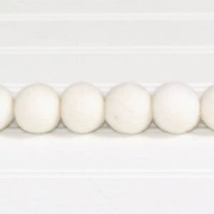 May include: Six white felt balls arranged in a row. The balls are smooth and round.