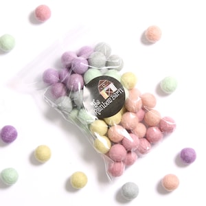 May include: A bag of pastel colored felt balls. The bag is clear plastic and has a sticker on it that says "The Rainbow Barn".