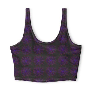 May include: A black crop top featuring a repeating pattern of spider webs in shades of purple and red. The garment has a scoop neckline, wide shoulder straps, and visible stitching along the edges, creating a consistent graphic design throughout.