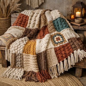 Könnte beinhalten: Eine handgefertigte Patchwork-Decke in einer Vielzahl warmer, erdiger Töne. Die Decke weist eine Mischung aus Texturen und Mustern auf, darunter Zopfmuster, Noppenstich und Fransen. Die Farbpalette umfasst Creme, Braun, Senf und Türkis.