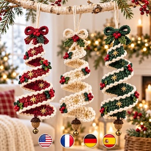 May include: Three spiral-shaped crochet Christmas tree ornaments hanging from a branch. Each features a top bow, red berry clusters, gold star embroidery, and a bottom acorn-shaped piece with a small metal bell. Colors are red, cream, and green.