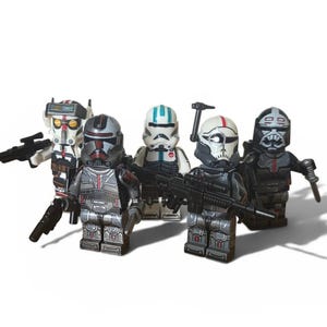 May include: Five plastic minifigures featuring detailed armour designs in shades of grey, white, black, and red. Each figure wears a distinct helmet and carries a small black plastic blaster accessory. The characters are arranged in a group formation.