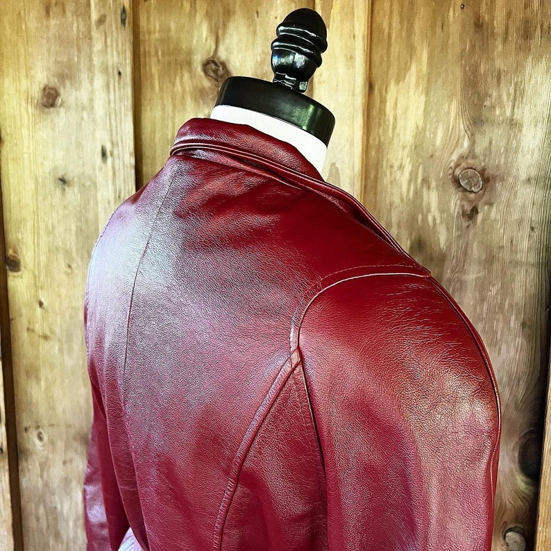 May include: A red leather jacket with a smooth, shiny finish. The jacket has a classic design with a stand-up collar and a zipper closure.