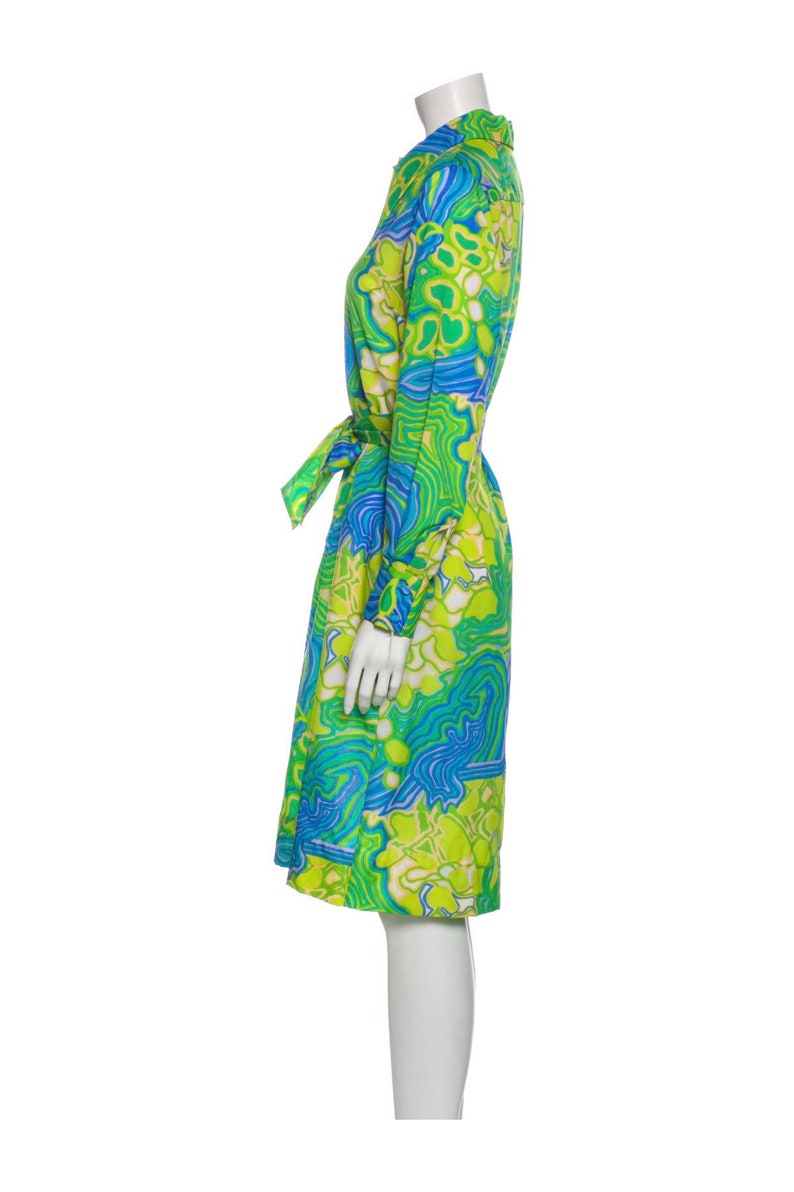 Pode incluir: Um vestido de manga comprida com estampa floral abstrata verde e azul. O vestido tem um cinto de amarra&ccedil;&atilde;o e uma gola.