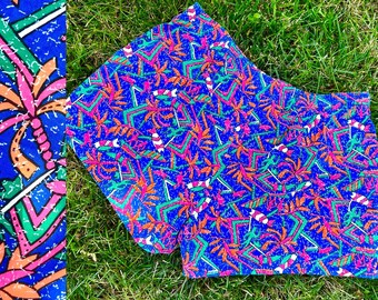 May include: A pair of blue and pink patterned shorts with a geometric design. The fabric has a distressed look and features a tropical palm tree motif.