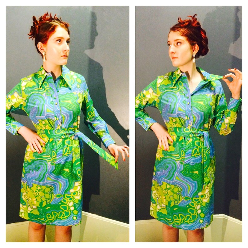Pode incluir: Um vestido estampado em verde e azul com gola e mangas compridas. O vestido tem um cinto e um padr&atilde;o abstrato em espiral.