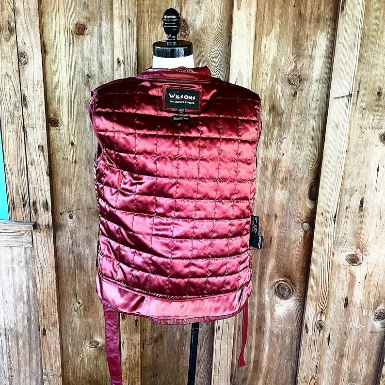 May include: A red leather vest with a quilted lining and a black leather label that says "WILSON'S THE GENUINE LEATHER" on the back.