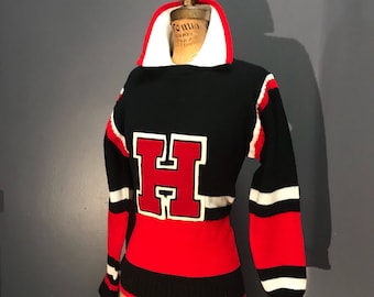 May include: Black, red, and white vintage sweater with a large red "H" on the front. The sweater has a collared neckline with a white interior and red trim. The sleeves have white and black stripes.