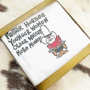 May include: A white square coaster with a gold border features a cartoon cowboy with a moustache and a red bandana. The text on the coaster reads "Faster Horses Younger Women Older Whisky More Money".