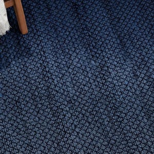May include: A deep navy blue area rug featuring a dense, textured weave with a consistent pattern of small, raised loops. The surface displays a uniform dark blue color throughout, creating a tactile and woven appearance across the entire visible area.