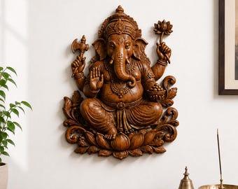 May include: A brown, carved wooden wall plaque depicting the deity Ganesha seated in a cross-legged position on a lotus flower base. The figure features four arms, holding an axe and a lotus flower, with intricate jewelry and a crown detail.