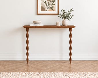 May include: A rectangular wooden console table with a smooth top and two distinct spiral-shaped legs. The table is finished in a warm brown tone and features a flat surface supported by two vertical, twisted columns that extend to the floor.