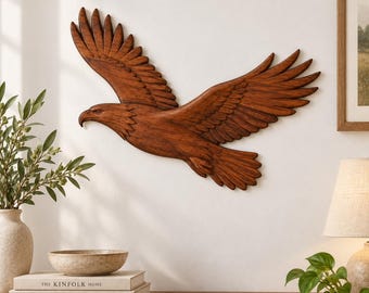 May include: A wall-mounted wooden eagle sculpture with outstretched wings, featuring detailed carved feathers and a rich brown finish. The eagle is depicted in a soaring position, showing a sharp beak and defined eye, crafted from wood.