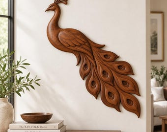 May include: A wall-mounted peacock sculpture carved from medium-brown wood. The piece features a detailed profile of the bird with a crest on its head and a long, flowing tail composed of multiple layered feathers, each displaying a carved eye pattern.