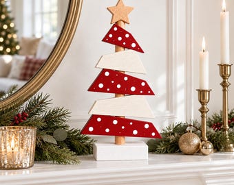 May include: A decorative wooden Christmas tree ornament featuring alternating red and white horizontal slats. The red slats are decorated with white polka dots. The tree is topped with a natural wood star and stands on a white base.