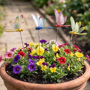 Peut inclure: Quatre tuteurs de jardin décoratifs en forme de libellule avec des ailes translucides multicolores et des corps en métal fin. Les libellules sont jaunes, bleues, rouges et jaunes, montées sur des tiges métalliques dans un pot en terre cuite.