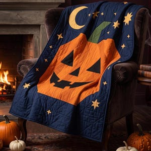Puede incluir: Una colcha azul marino que presenta una gran calabaza naranja con ojos, nariz y boca dentada de color negro. La colcha está decorada con una luna creciente amarilla y varias estrellas amarillas sobre el fondo azul oscuro.
