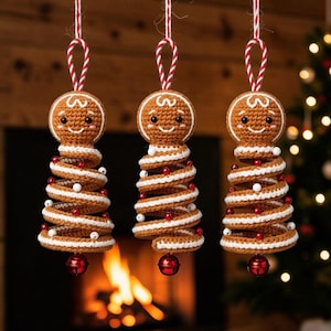 May include: Three crocheted gingerbread ornaments hanging from red and white striped strings. Each ornament features a round gingerbread head with a smiling face and a spiral-shaped body decorated with white icing trim, small red beads, and white beads.
