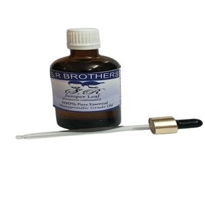 Könnte beinhalten: Eine braune Glasflasche mit weißem Verschluss und einem Etikett mit der Aufschrift S.R BROTHERS Juniper Leaf (Juniperus communis) 100% Pure Essential Therapeutic Grade Oil. Eine klare Glastropfpipette mit goldfarbenem Ring und schwarzem Kopf.