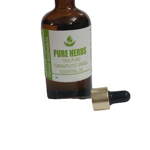 May include: An amber glass bottle with a white cap containing essential oil, featuring a label that reads Pure Herbs 100% Pure Therapeutic Grade Essential Oil Asafoetida Ferula asafoetida. A separate gold and black dropper top sits beside the bottle.