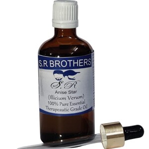 Op de afbeelding: Een bruine glazen fles met een witte dop en een etiket met de tekst S.R BROTHERS, Anise Star (Illicium Verum) 100% Pure Essential Therapeutic Grade Oil. Een glazen pipet met een goudkleurige kraag en een zwarte rubberen dop ligt ervoor.