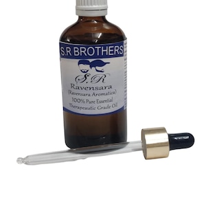 May include: A brown glass bottle of S.R Brothers Ravensara Aromatica 100% pure essential therapeutic grade oil with a white screw cap, accompanied by a glass dropper with a gold-colored collar and a black rubber bulb.