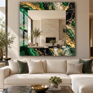 May include: A square wall mirror featuring a decorative frame with a marbled pattern in shades of emerald green, black, and gold. The reflective center displays a room interior with a fireplace, a potted plant, and neutral furniture.