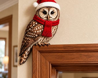 May include: A brown and white owl figurine perched on the corner of a wooden door frame. The owl is wearing a red and white Santa hat and a bright red knitted scarf around its neck. The owl has large dark eyes and detailed feather patterns.