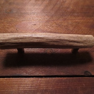 May include: A light brown antler drawer pull with metal hardware.