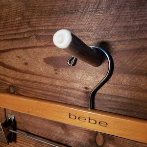 May include: A wooden hanger with a metal hook and the word "bebe" printed on it.