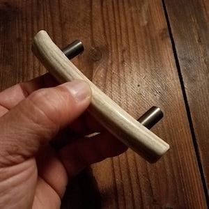 May include: A curved antler handle with a light brown and white pattern and two silver metal screws.