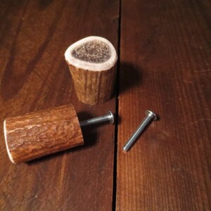 Puede incluir: Dos pomos de asta de ciervo con un tornillo plateado y un tornillo plateado con cabeza redonda. Los pomos son de asta de ciervo natural y tienen un color marrón.