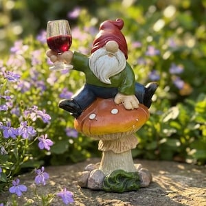 May include: A garden gnome figurine with a red hat, white beard, green shirt, and blue pants, sitting on a spotted orange mushroom. The gnome holds a clear glass filled with red liquid, appearing to toast with the drink while perched on the fungus.